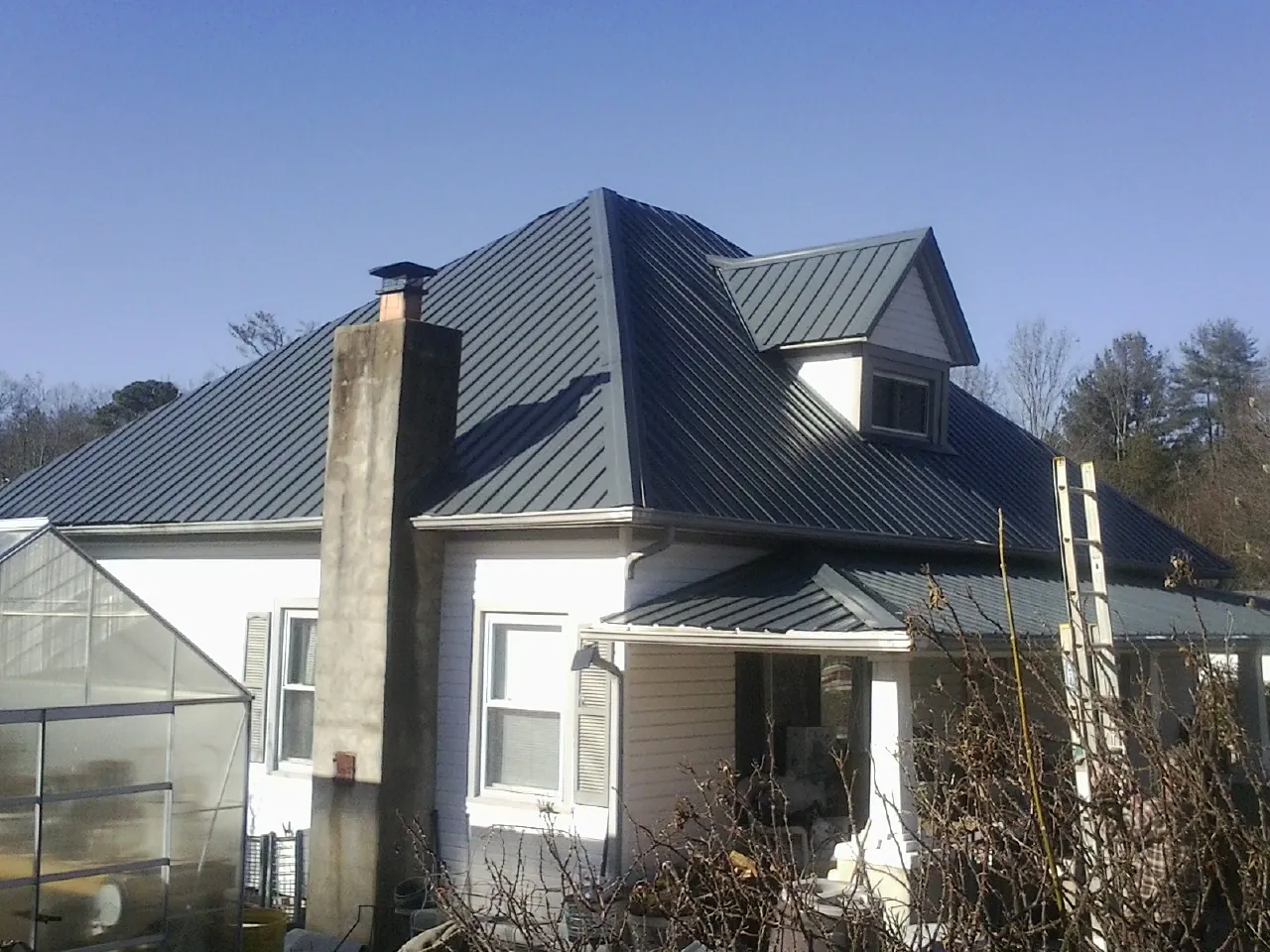 Dark blue standing seam metal roof on a white farmhouse with dormer — Slate & Tile Roof Repair by Roofing Brothers in Ahsahka