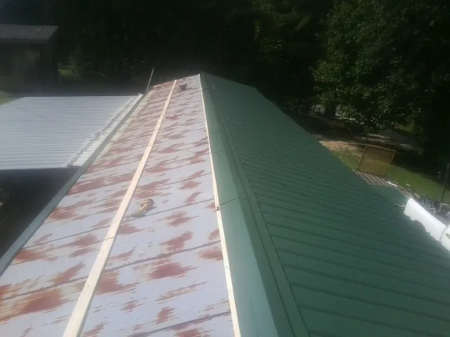 Old rusted panels beside newly installed green metal roofing — Wind Damage Roof Repair by Roofing Brothers in Ahsahka