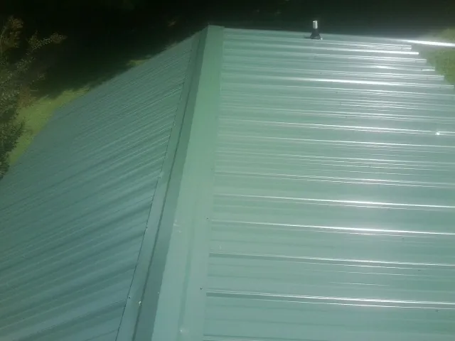 New green metal panels meeting at the ridge of a roof — Flat Roof Repair work by our crew in Ahsahka