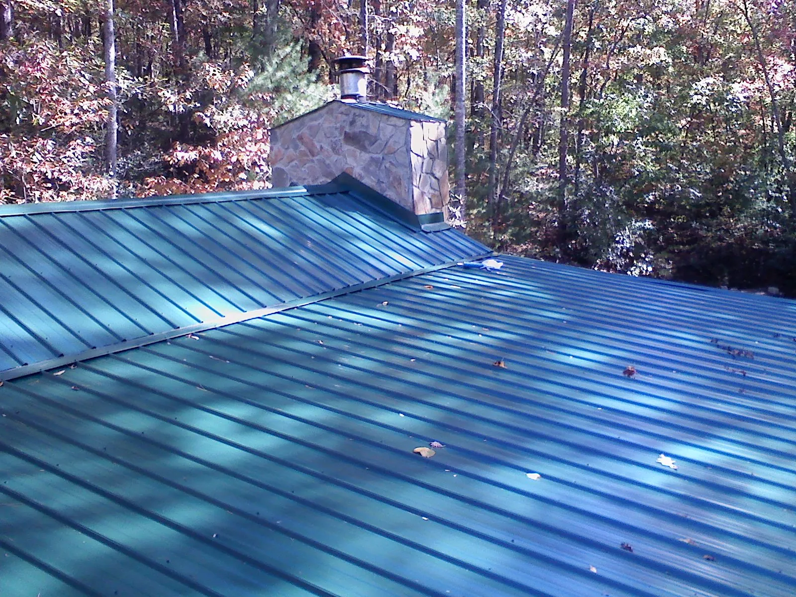New green metal roof and stone chimney surrounded by autumn woods in Ahsahka