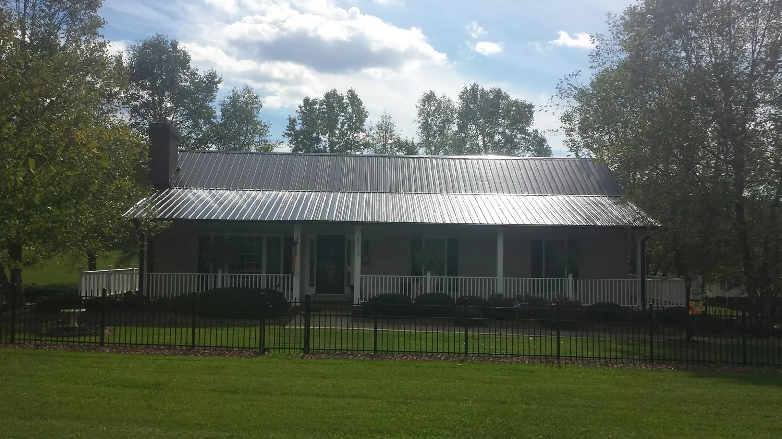 Gray metal roof on a brick ranch with a full width front porch — Gutter Guard Installation work by our crew in Ahsahka