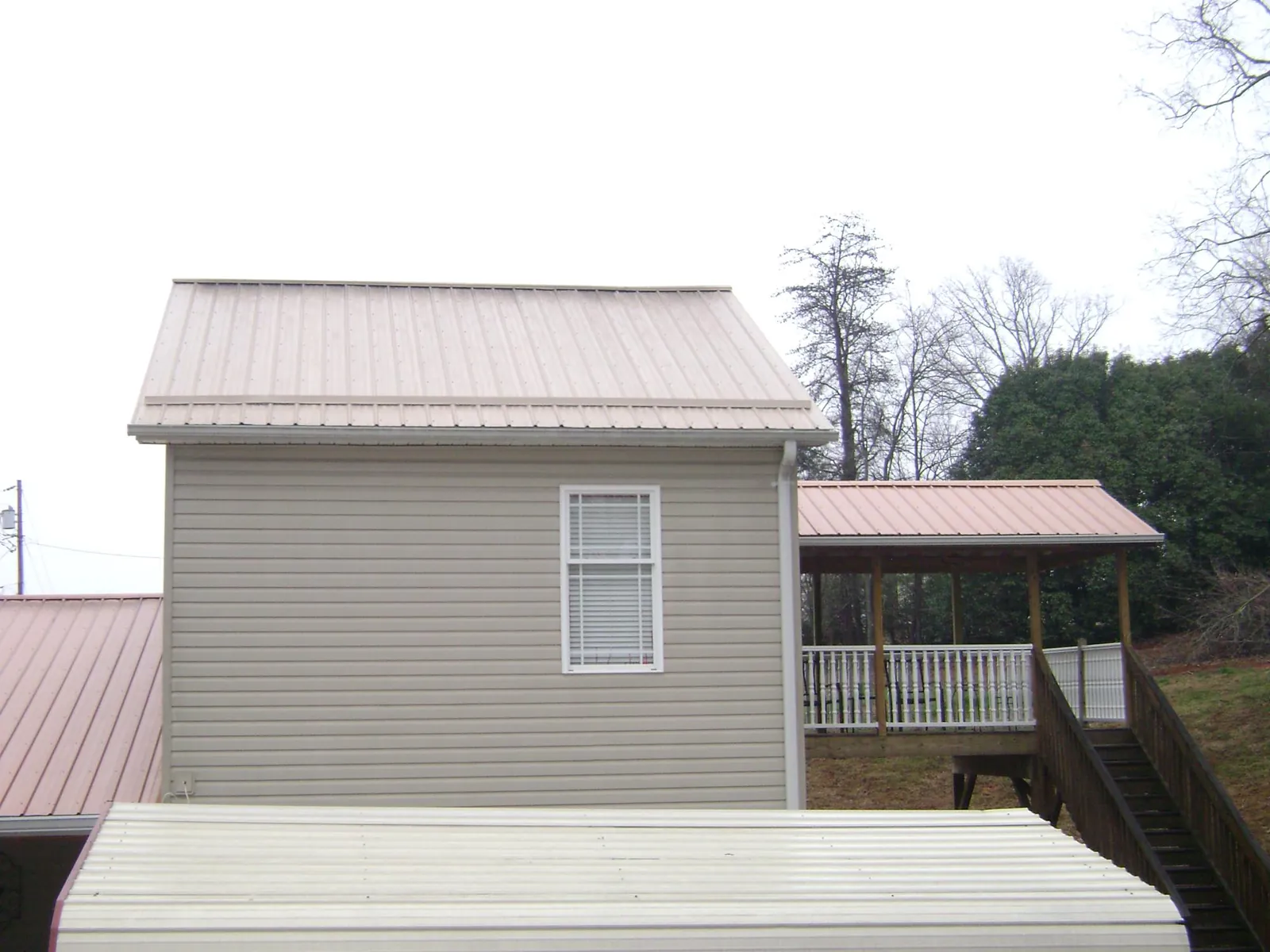Tan metal roofs on a two story addition and attached porch, from a Roof Replacement job in Ahsahka