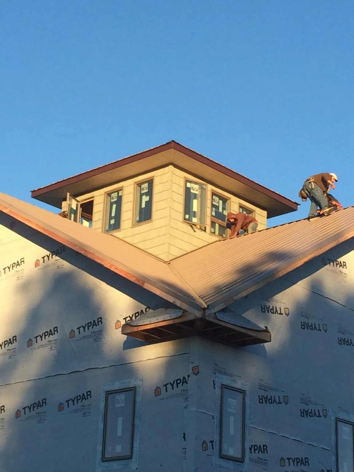 Roofers working around a rooftop cupola on a new metal roof at sunset — Roof Waterproofing in Ahsahka by Roofing Brothers